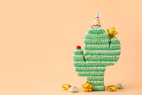 Mexican pinata in shape of cactus with party hat and balloons on color background - Фото, изображение