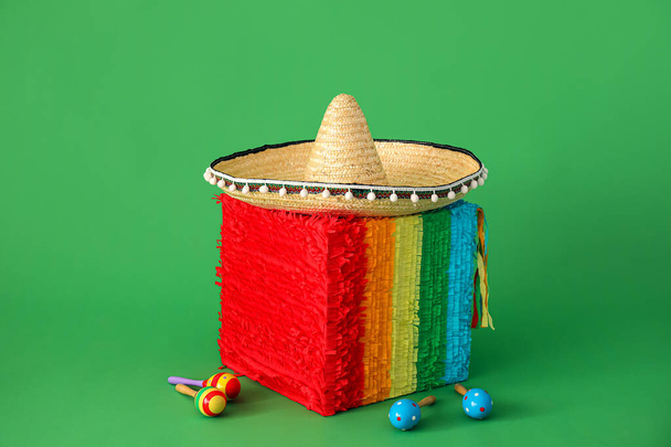 Pinata mexicana en forma de cubo con sombrero sombrero y maracas sobre fondo verde - Foto, Imagen