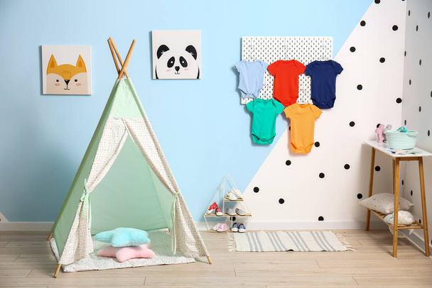 Interior of stylish children's room with pegboard, baby bodysuits and play tent - Photo, Image