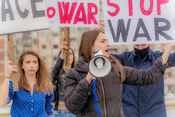 Een groep mooie jongeren protesteert samen op straat tegen de oorlog terwijl ze schreeuwen: - Foto, afbeelding