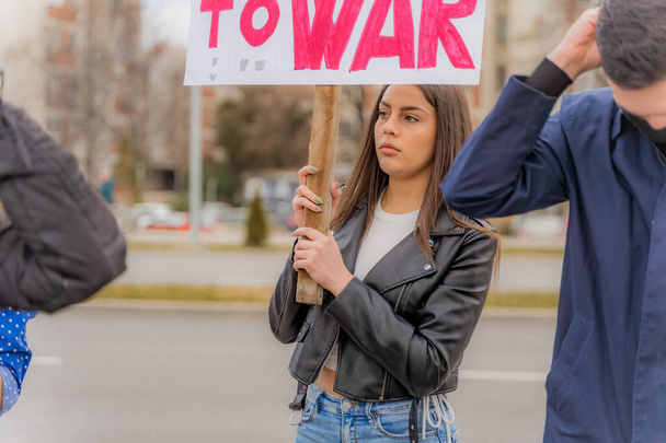 Красивая и молодая девушка держит знак протеста на улице - Фото, изображение