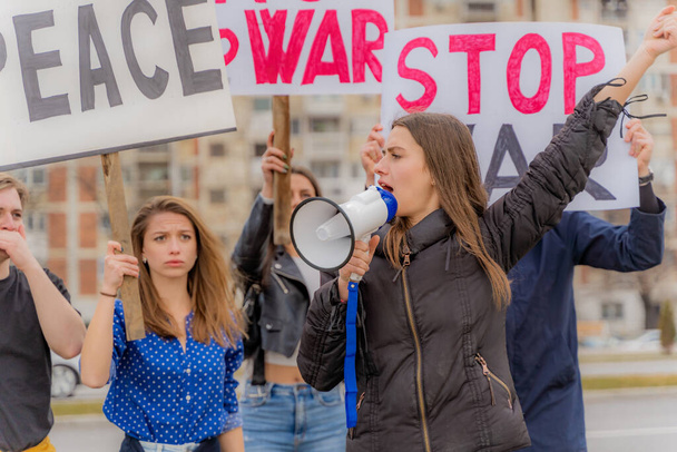 Ομάδα όμορφων νέων διαδηλώνουν ενάντια στον πόλεμο μαζί στο δρόμο, κοντά. - Φωτογραφία, εικόνα