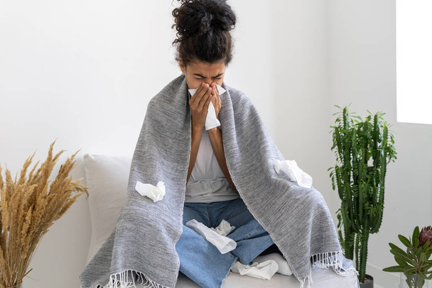 Portrait of young afro american girl suffering from flu and sneezing in handkerchief. Running nose. Medicine and healthcare concept. Coronavirus disease - Photo, image