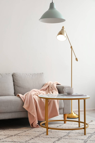 Belső tér világos nappali szürke kanapéval, asztal és lámpák - Fotó, kép