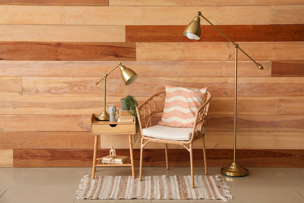 Интерьер стильной гостиной с плетеным креслом, деревянным столом и золотыми лампами - Фото, изображение