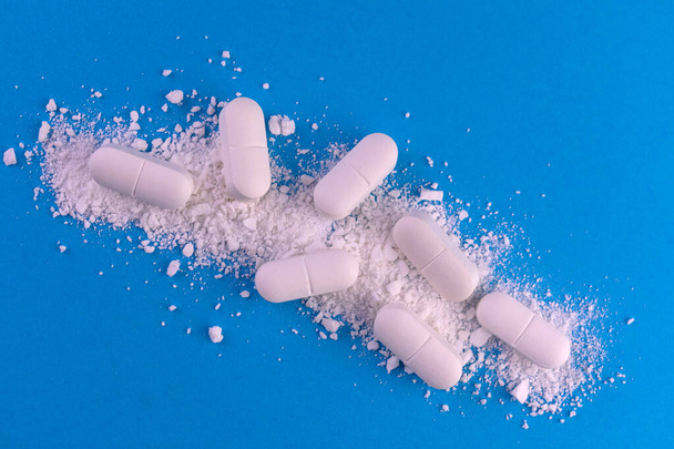 Medical background from crushed pills on a blue background - Photo, image