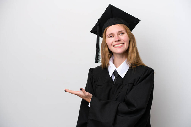 Jeune diplômée universitaire anglaise isolée sur fond blanc présentant une idée tout en regardant souriant vers - Photo, image