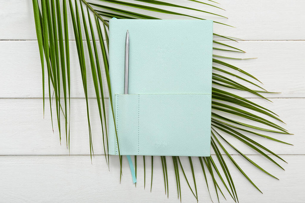 Stílusos notebook toll és pálmalevél fehér fa háttér - Fotó, kép