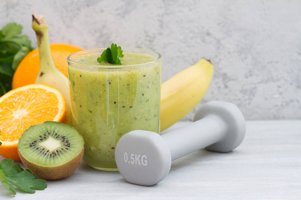 Fresh green smoothie, fruits and dumbbells, healthy food and sport concept - Zdjęcie, obraz