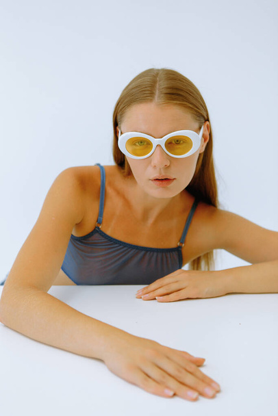Művészeti portré egy lány sárga szemüveg fehér háttér  - Fotó, kép
