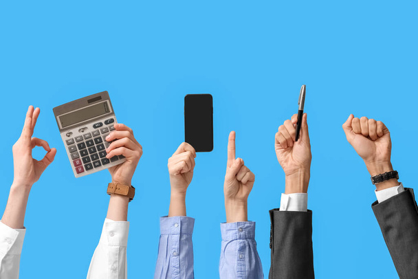 Gente de negocios con calculadora, teléfono móvil y pluma sobre fondo azul - Foto, Imagen