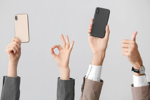 Деловые люди с мобильными телефонами жестом на светлом фоне - Фото, изображение