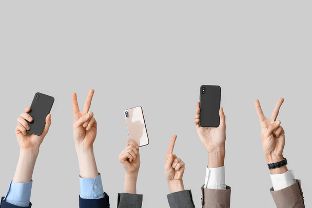 Geschäftsleute mit Mobiltelefonen gestikulieren auf hellem Hintergrund - Foto, Bild