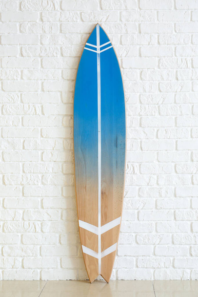 Nowoczesna deska surfingowa w pobliżu ściany z białej cegły w pokoju - Zdjęcie, obraz