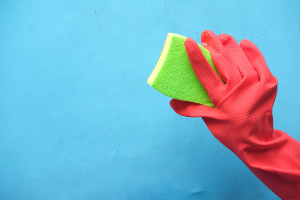  hand in rubber gloves holding sponge on blue background with copy space  - Fotó, kép