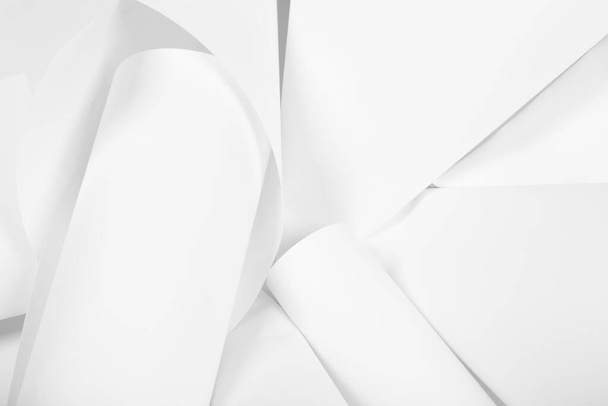Bílé listy kancelářského papíru jsou pokroucené a roztroušené. Bílé abstraktní pozadí papíru. - Fotografie, Obrázek