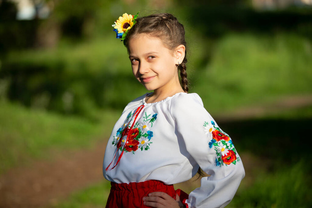 A little Ukrainian and Belarusian girl in an embroidered shirt on a summer background. - Foto, Imagen