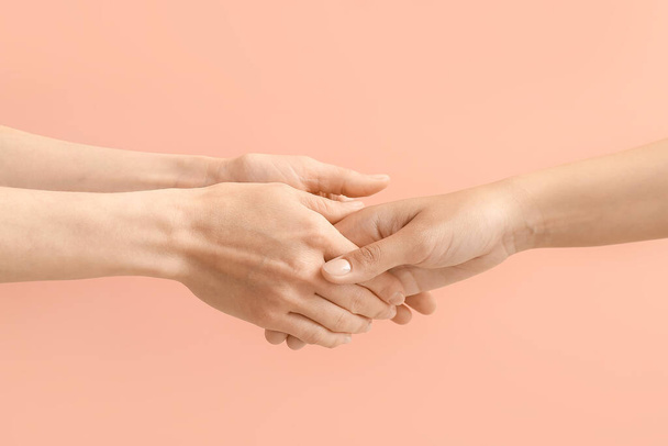 Women holding hands together on color background - Photo, Image