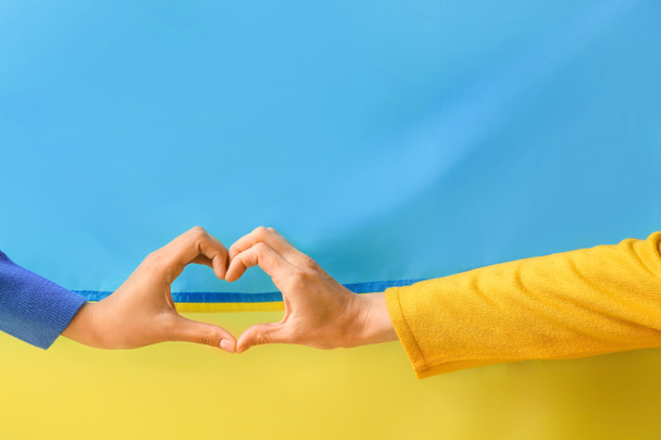 Mains montrant la forme du cœur contre le drapeau de l'Ukraine - Photo, image