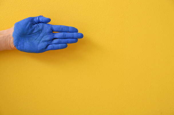 Mão com palma azul pintada sobre fundo amarelo - Foto, Imagem