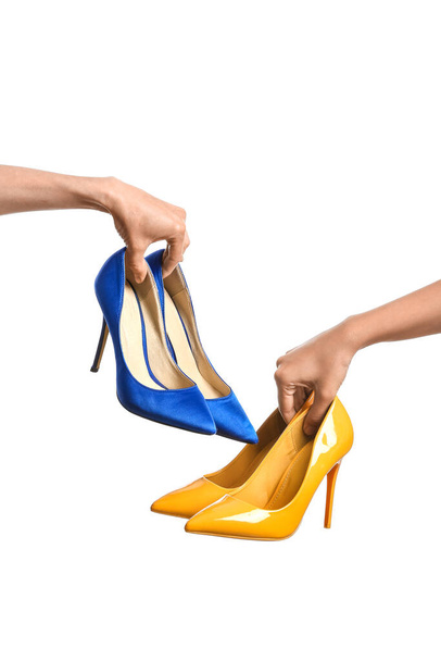 Female hands holding stylish high-heels in colors of Ukrainian flag on white background - Фото, изображение