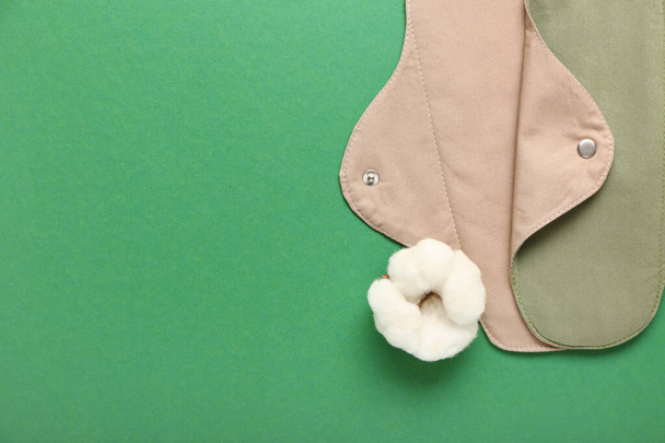 Vratné menstruační podložky a bavlněné květy na zeleném pozadí - Fotografie, Obrázek
