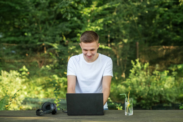 Young guy smiles happily while making video call using laptop. - Photo, image