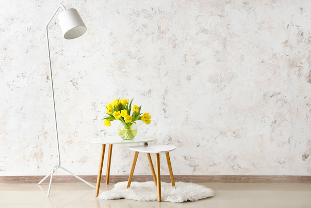 Kávové stoly s květinami ve váze a standardní lampy u světelné stěny - Fotografie, Obrázek