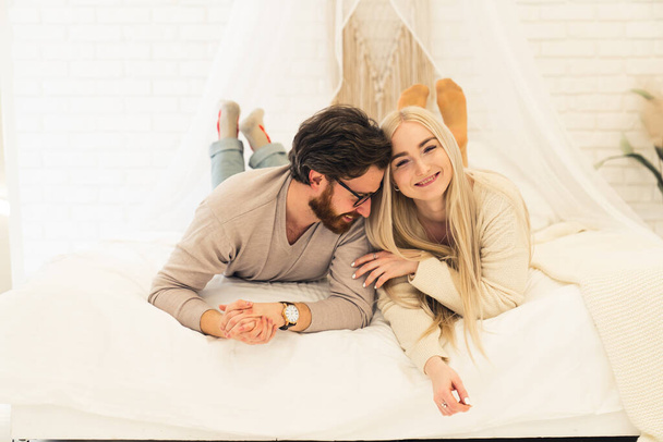 cheerful brunet with his lovely long-haired girlfriend laying on bed, joking, and smiling - Foto, Bild