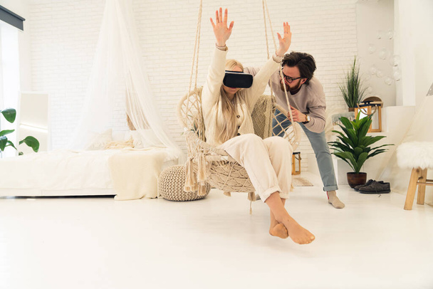 young caucasian woman beginning her adventures with virtual reality goggles with the help of her husband - Photo, Image