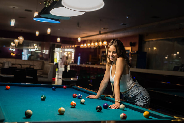 Ładna kobieta spędza wolny czas grając w bilard w pubie. koncepcja gry - Zdjęcie, obraz