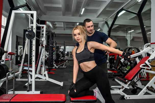 happy healthy friendly male trainer conducts personal training with beautiful client. The concept of physical training in the gym on personal training - Photo, Image