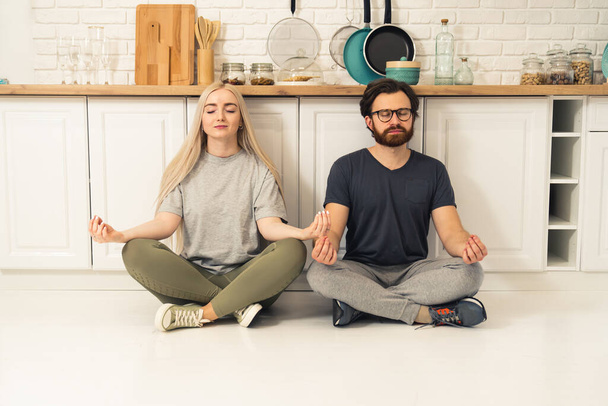 счастливая кавказская пара медитирует на карантине в своей современной квартире, заботясь о физическом и психическом здоровье - Фото, изображение