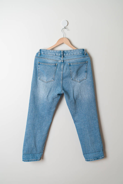 jeans trousers hanging with wood hanger on wall - Foto, immagini