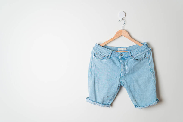 short pants jeans hanging with wood hanger on wall - 写真・画像