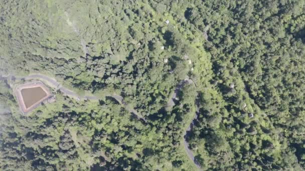 Лети по звивистій дорозі, проходячи буйною рослинною тропічною зоною, згори вниз повітряної зйомки Ката Сай Юань. Тропічні ліси, що покривають схил пагорба, вид зверху. Камера повертає і йде по кривій проїжджої лінії - Кадри, відео