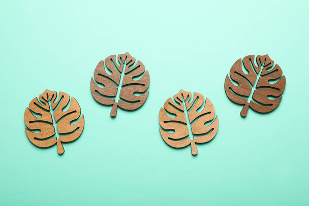 Leaf shaped wooden cup coasters on turquoise background, flat lay - Фото, зображення