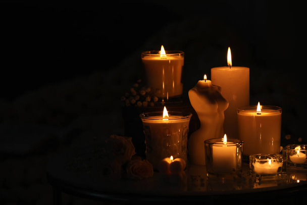 Beautiful burning candles on table in darkness. Space for text - Φωτογραφία, εικόνα