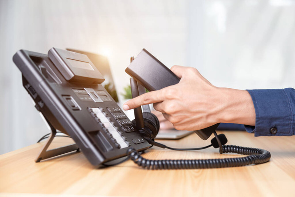 Puhelinkeskuksen henkilökunnan käsi osoittaa painamalla puhelimen toimiston työpöydän nappia, viestintätukea, puhelinpalvelukeskusta ja asiakaspalvelua. varten (Call Center) käsite - Valokuva, kuva