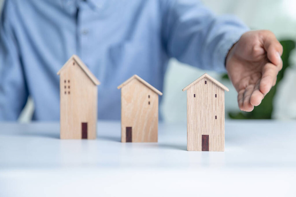 Podnikatel výběr mini dřevěný dům model z modelu na dřevěném stole, Plánování koupit nemovitost. koncept Vyberte to nejlepší. - Fotografie, Obrázek