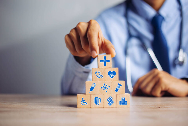 Рука організовує укладання дерев'яного блоку з іконою медичного страхування, страхування для вашого здоров'я медичного, страхування для вашої концепції охорони здоров'я
. - Фото, зображення