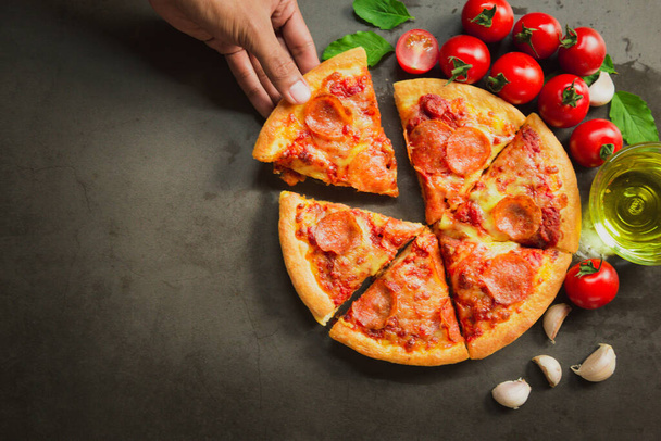 Vista superior de la pizza de pepperoni caliente, sabrosa pizza de pepperoni e ingredientes de cocina tomates albahaca sobre fondo negro. - Foto, imagen