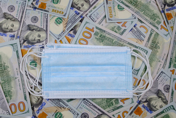 お金を背景にフェイスマスク。コロナウイルスの概念 - 写真・画像
