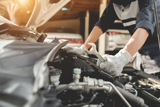 Automobiel monteur reparateur handen repareren van een auto-motor automotive workshop met een moersleutel, auto service en onderhoud, Reparatie service. - Foto, afbeelding