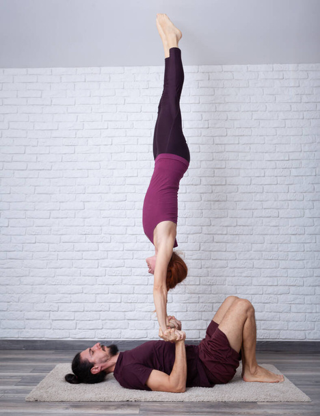 Jeune couple s'amusant à la maison avec quelques poses d'acro yoga dans différents endroits
. - Photo, image