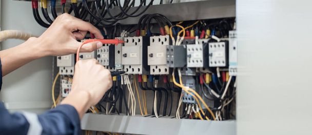 Testeur de travail ingénieur électricien mesurant la tension et le courant de la ligne électrique dans le contrôle de l'armoire électrique, contrôle de concept le fonctionnement du système électrique . - Photo, image