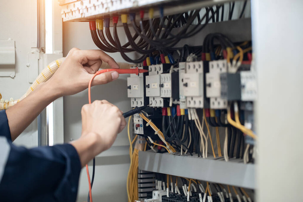 Electrician engineer work tester measuring voltage and current of power electric line in electical cabinet control , concept check the operation of the electrical system . - Photo, Image