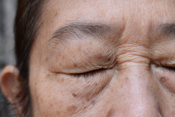 Falten um das geschlossene Auge einer asiatischen älteren Frau. Nahaufnahme. - Foto, Bild