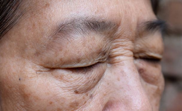 Falten um das geschlossene Auge einer asiatischen älteren Frau. Nahaufnahme. - Foto, Bild