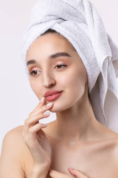 Beautiful girl with thick eyebrows and perfect skin at white background, towel on head, beauty photo. - Valokuva, kuva